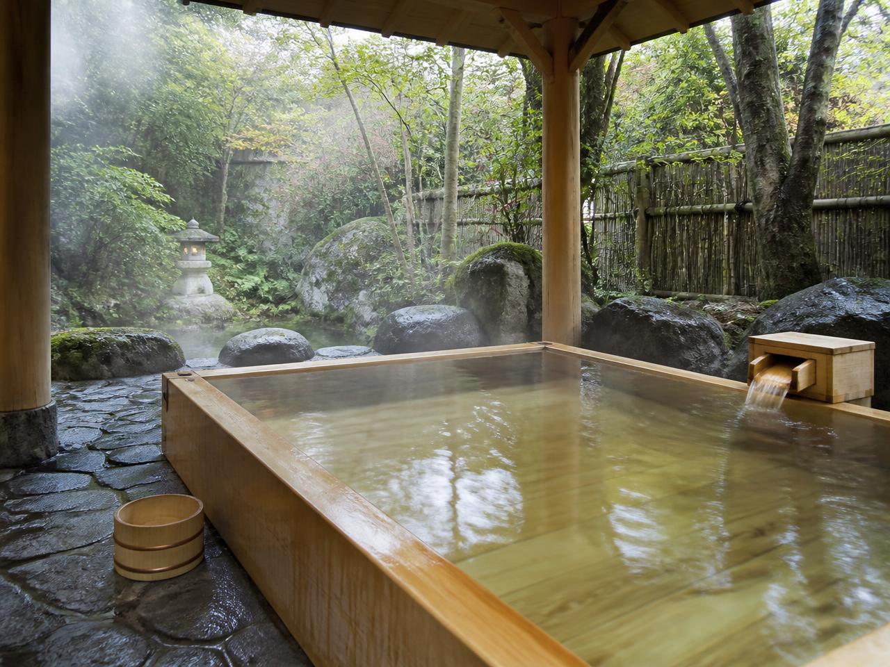 Private hinoki wood onsen bath surrounded by mossy stones
