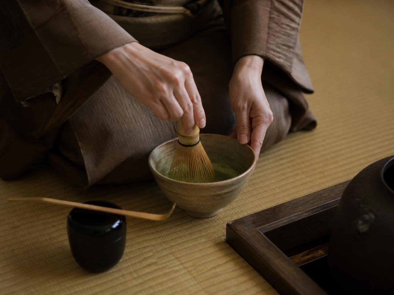 Hands whisking matcha during a tea ceremony on tatami